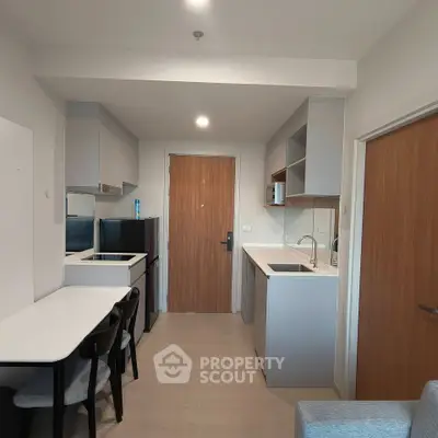 Modern kitchen with sleek cabinetry and dining area in a compact apartment layout.