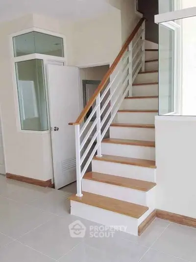 Modern staircase with wooden handrail in bright interior space