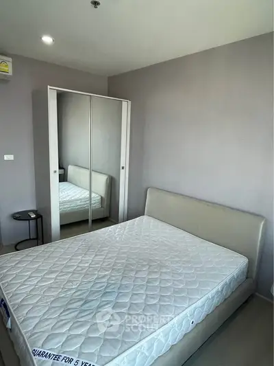 Modern bedroom with mirrored wardrobe and comfortable bed in a stylish apartment.