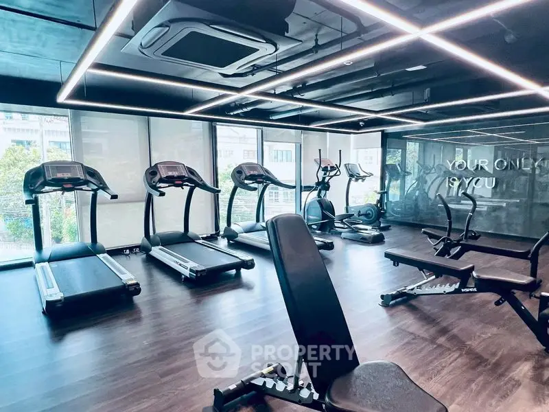 Modern gym with state-of-the-art equipment and large windows for natural light.
