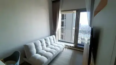 Modern living room with a cozy sofa and balcony view in a high-rise apartment.