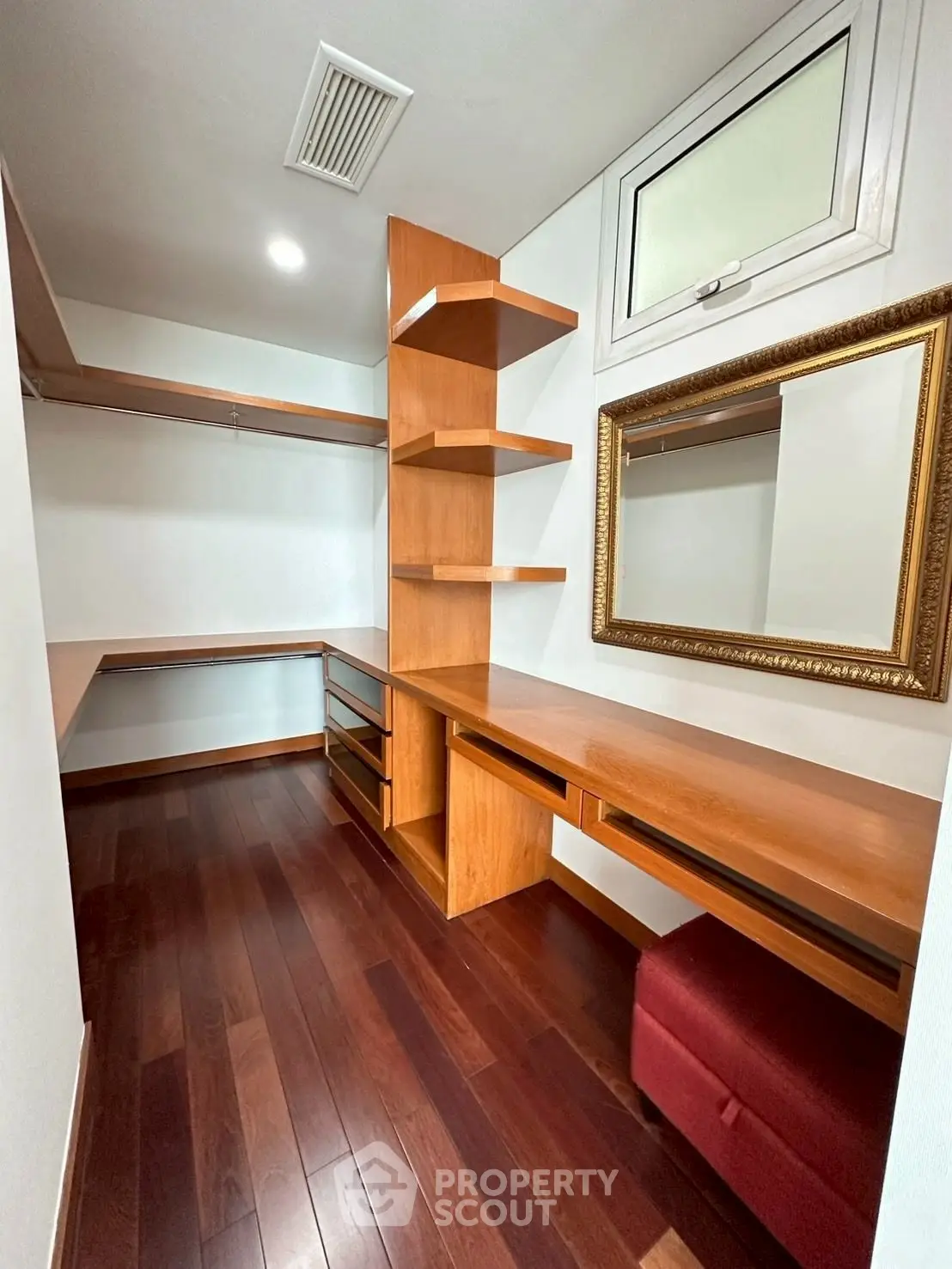 Spacious walk-in closet with wooden shelves and elegant mirror, perfect for organized storage.