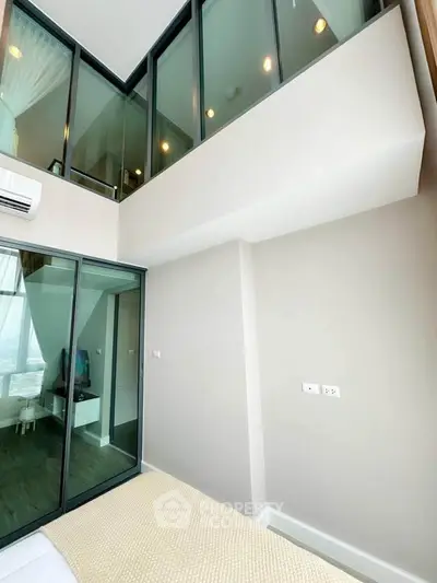 Modern high-ceiling bedroom with glass walls and natural light