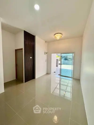 Spacious modern living room with elegant chandelier and large sliding glass doors.
