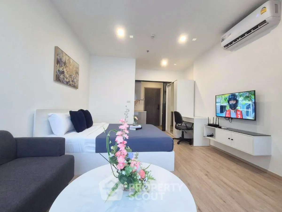 Modern studio apartment with stylish decor and cozy living area, featuring a comfortable bed and wall-mounted TV.