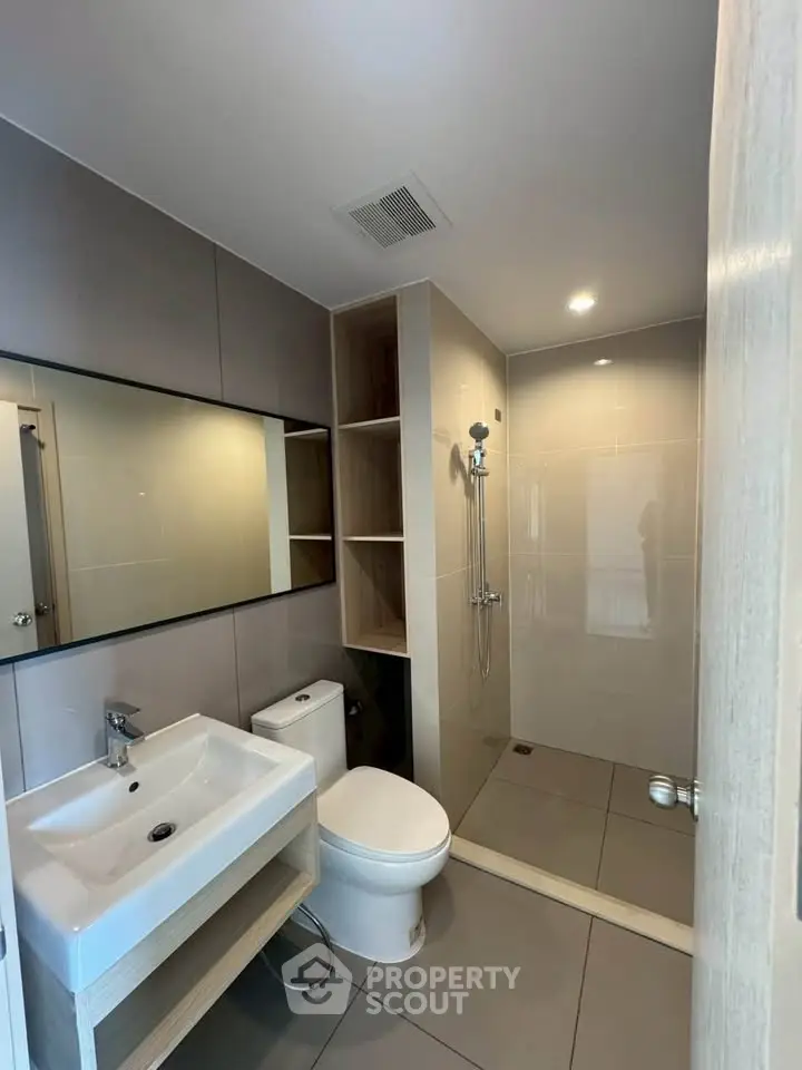 Modern bathroom with sleek fixtures and spacious shower area in contemporary apartment.