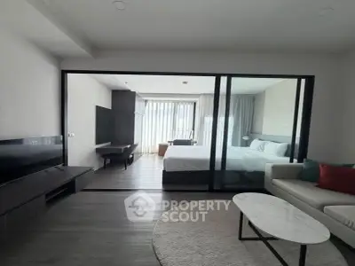 Modern studio apartment with glass partition, cozy living area, and stylish bedroom.