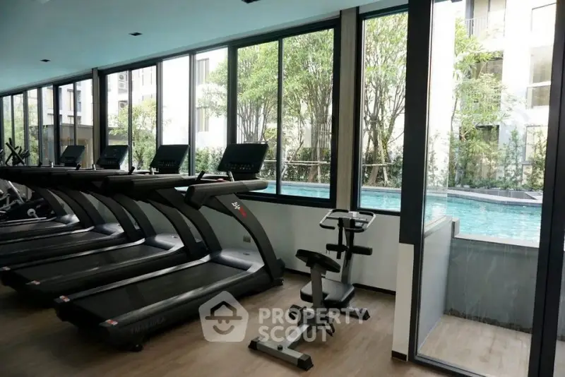 Modern gym with treadmills overlooking a serene pool view, perfect for fitness enthusiasts.