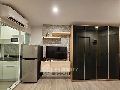 Modern living room with sleek TV setup and adjacent kitchen area, featuring stylish cabinetry and appliances.