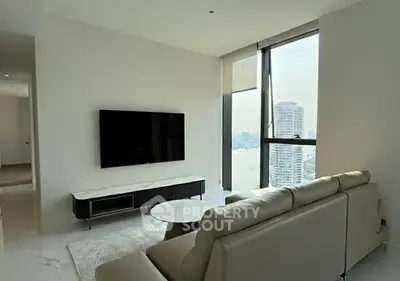 Modern living room with sleek furniture and stunning city view through large windows.
