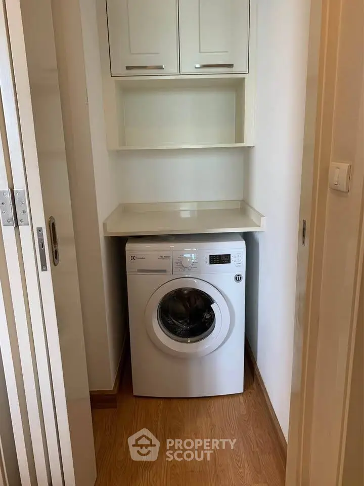 Compact laundry area with modern washing machine and storage cabinets.