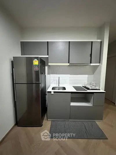 Modern compact kitchen with sleek cabinetry and stainless steel fridge