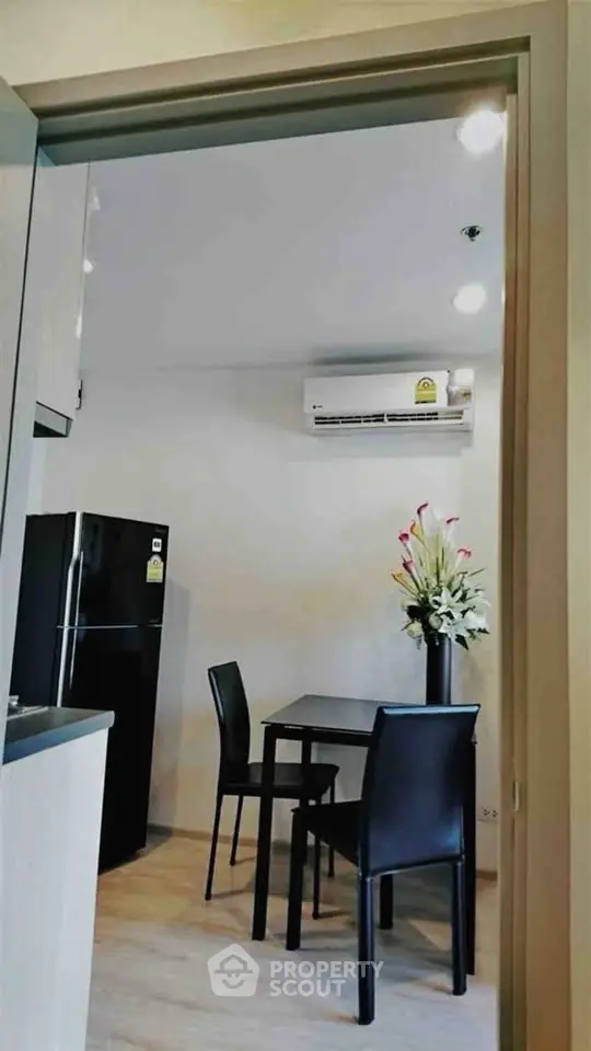 Modern kitchen with dining area featuring sleek black furniture and air conditioning.