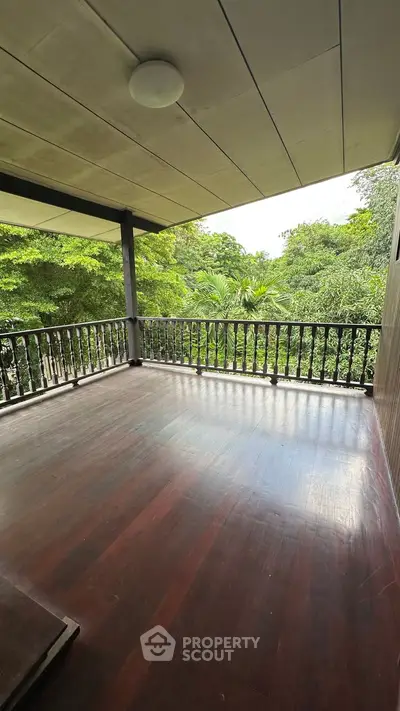Spacious wooden balcony with lush green views, perfect for relaxation and outdoor enjoyment.