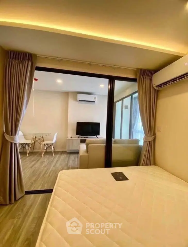 Modern apartment interior with open living room and bedroom, featuring sleek design and ample natural light.