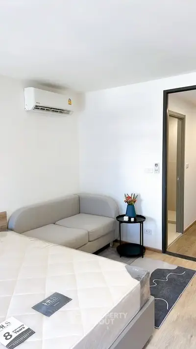 Modern bedroom with cozy sofa and air conditioning in a stylish apartment.