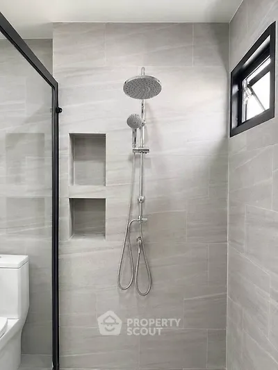 Modern bathroom with sleek shower and neutral tiles, featuring a minimalist design and natural light.