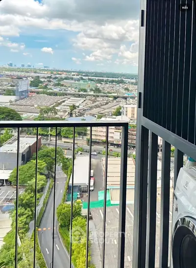 Stunning high-rise balcony view overlooking cityscape with lush greenery and urban skyline.