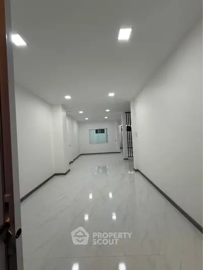 Spacious empty room with glossy marble flooring and bright recessed lighting.