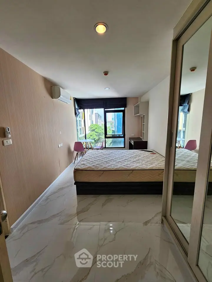 Modern bedroom with large window and city view, featuring a comfortable bed and stylish decor.