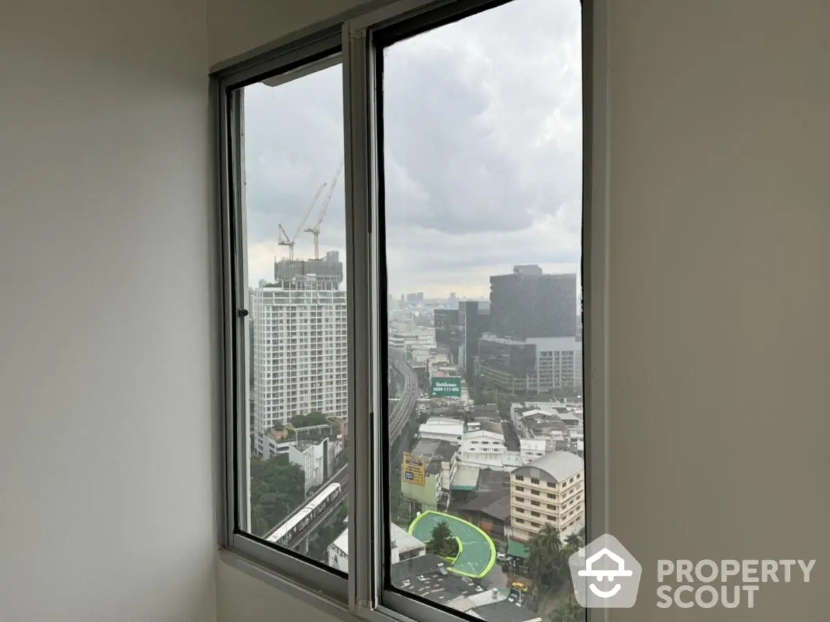 High-rise urban view from apartment window showcasing cityscape and construction cranes.