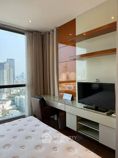 Modern bedroom with city view, featuring a sleek desk and TV setup, ideal for urban living.
