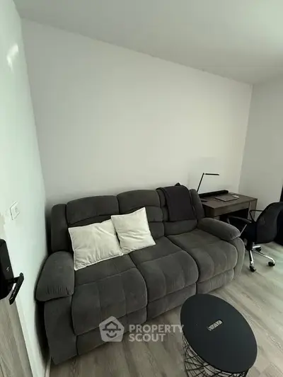 Modern living room with cozy sofa and stylish workspace setup.