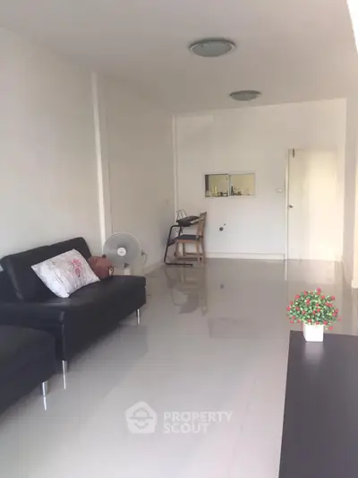 Spacious living room with sleek black sofa and glossy tiled floor