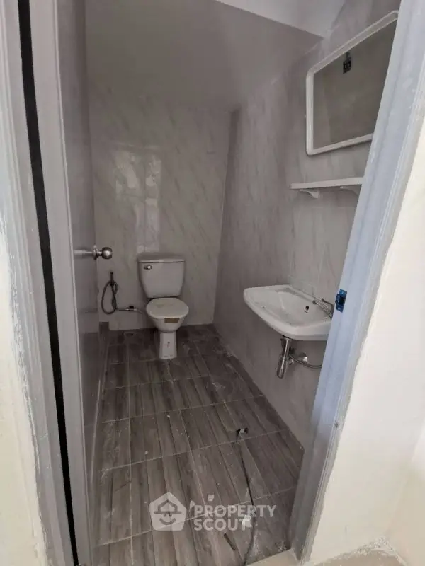 Compact bathroom with modern fixtures and marble walls, featuring a toilet and sink.