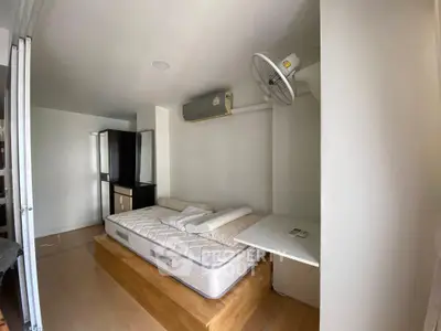 Compact bedroom with elevated platform bed and wall-mounted fan in modern apartment.
