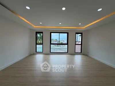 Spacious empty room with large windows and modern lighting, offering a serene view.