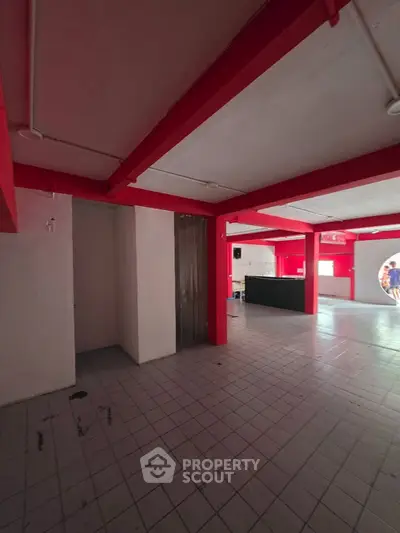 Spacious commercial interior with red beams and tiled flooring, ideal for retail or office space.