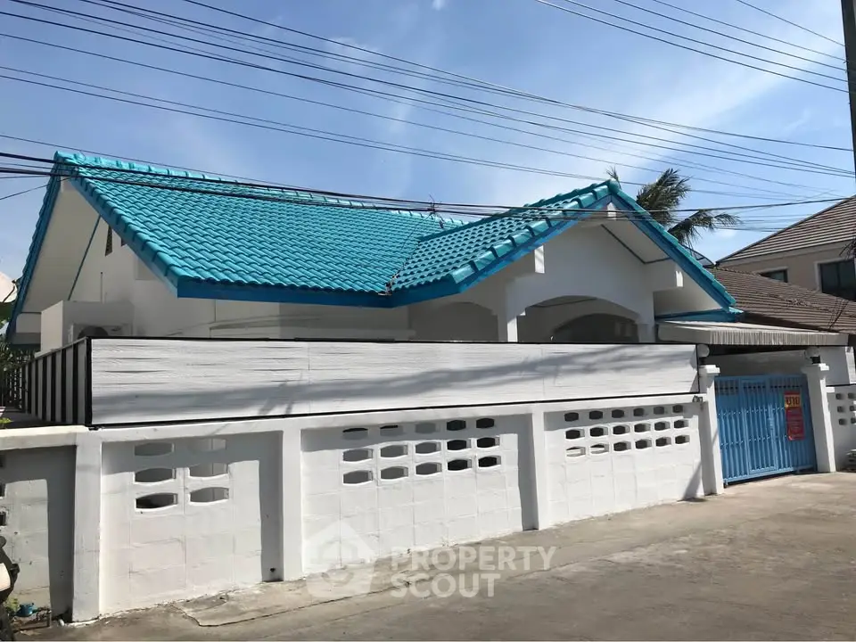 Charming white house with blue roof and gated entrance in a serene neighborhood.