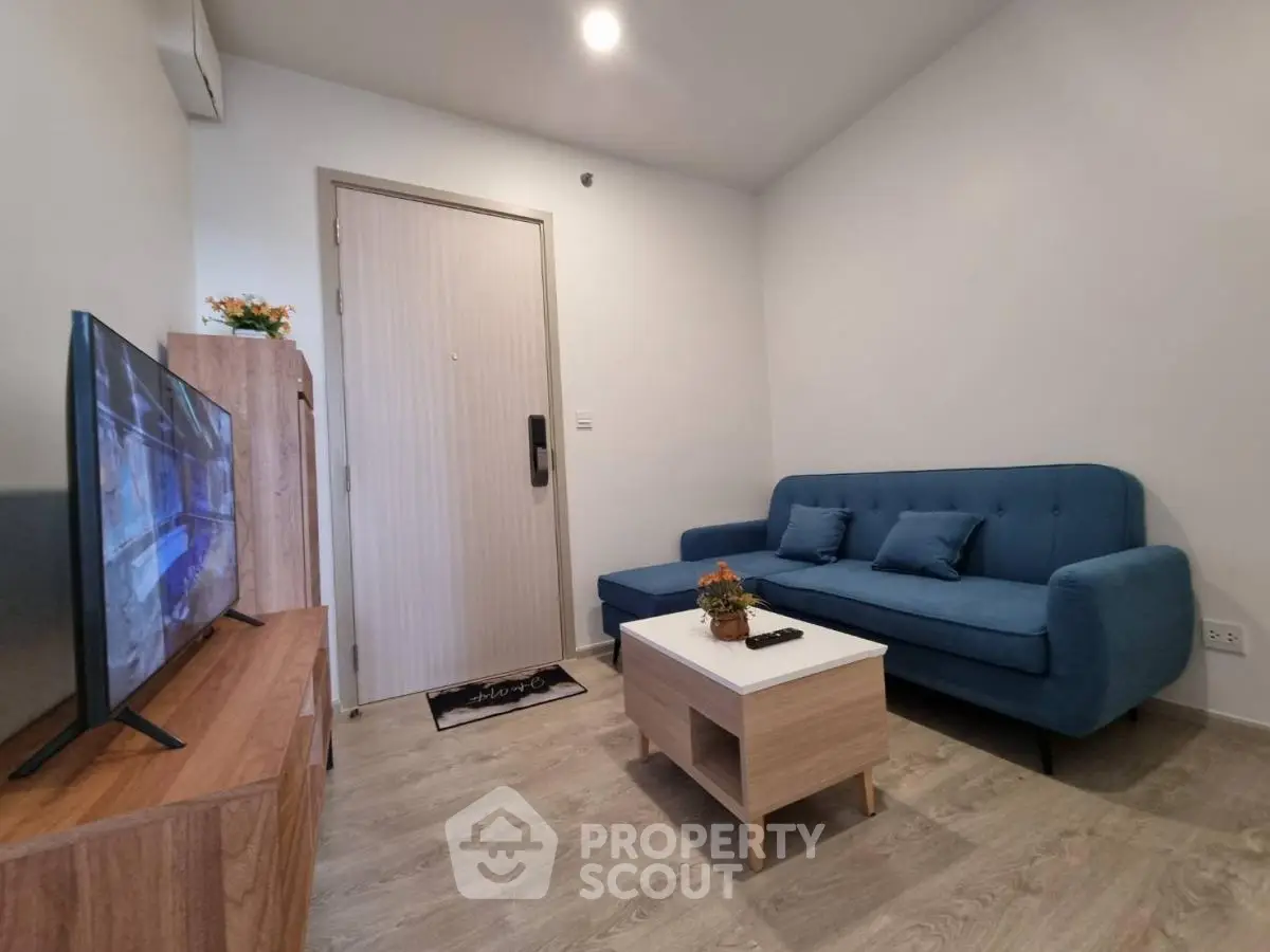 Modern living room with blue sofa and flat-screen TV in stylish apartment