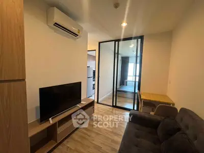 Modern living room with sleek furniture and glass partition leading to bedroom