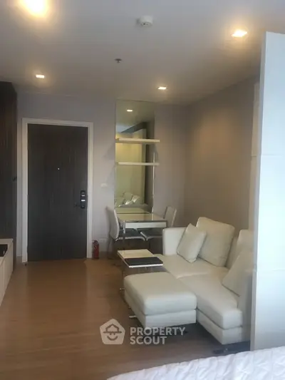 Modern living room with white leather sofa and dining area in stylish apartment