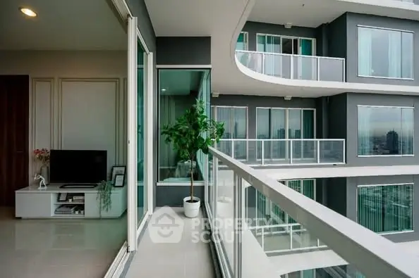 Modern apartment with spacious balcony and city view, featuring sleek design and large glass doors.