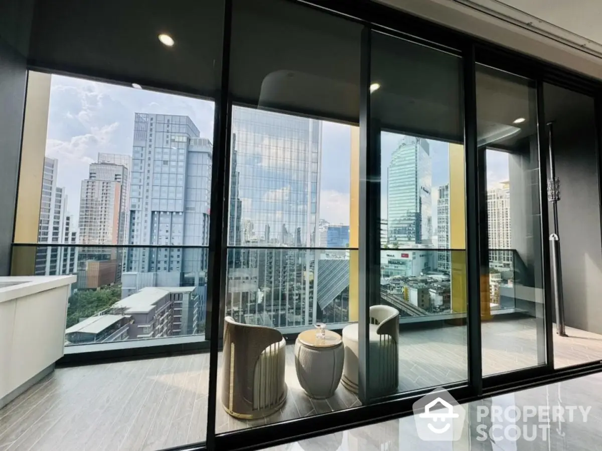 Luxurious balcony with stunning city view and modern seating area in high-rise apartment.