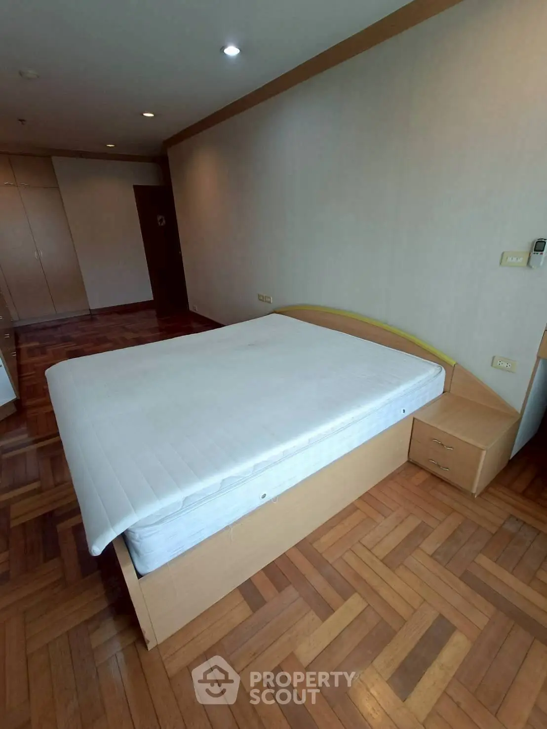 Spacious bedroom with wooden flooring and modern furnishings in a stylish apartment.