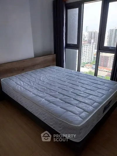 Spacious bedroom with large window offering city view and natural light.