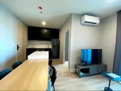 Modern living room with open kitchen, featuring sleek furniture and air conditioning.