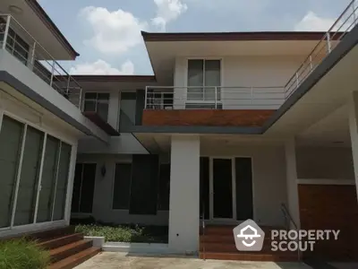 Modern two-story house with balcony and large windows under a clear sky.