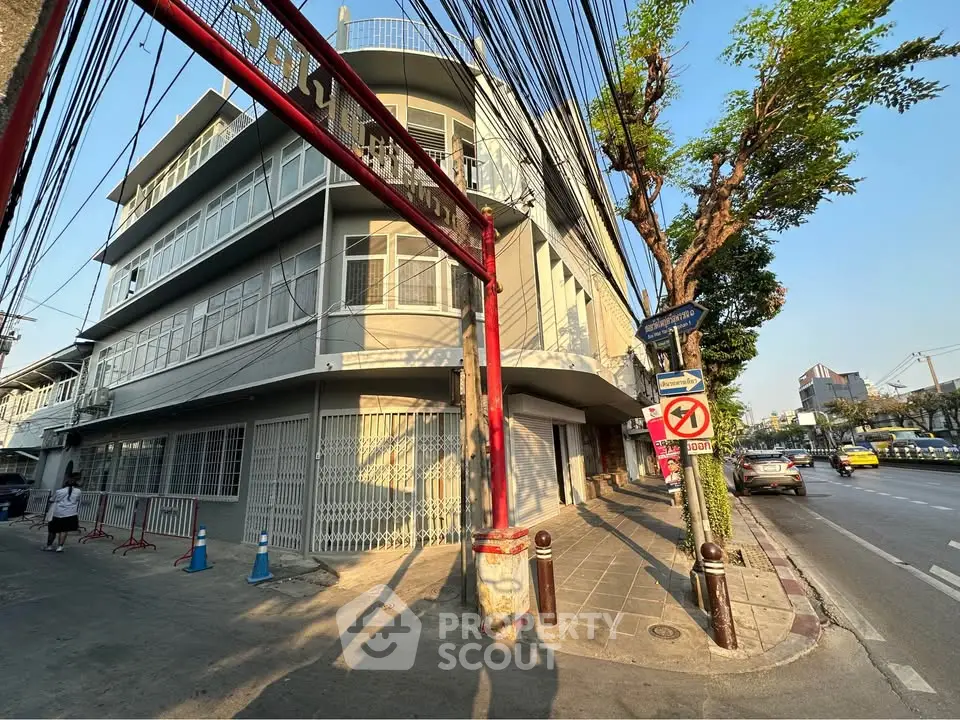 Corner building with modern facade on a sunny street, showcasing urban architecture and city life.