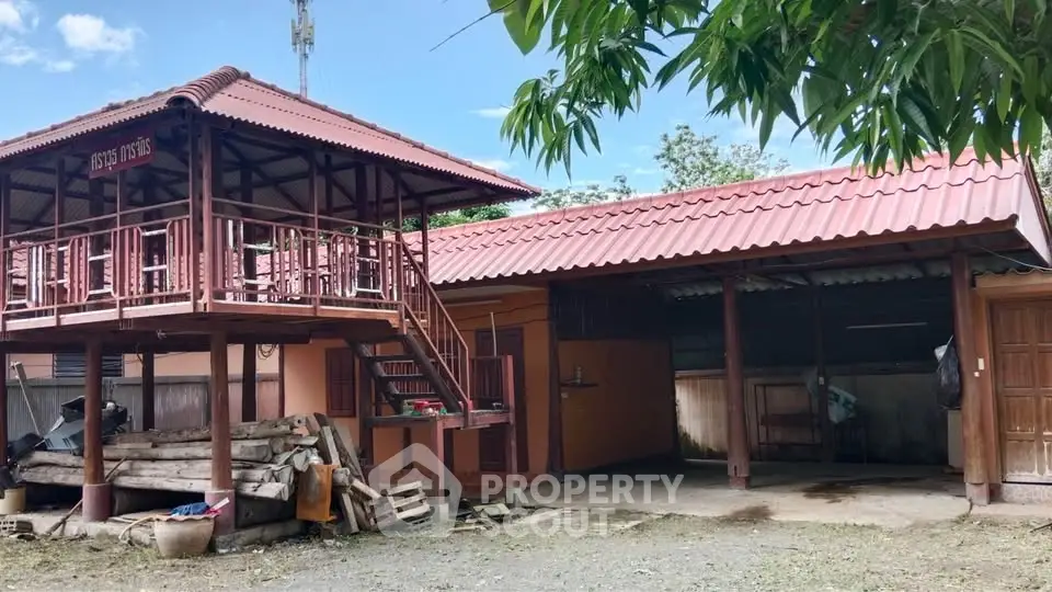 Charming rustic two-story house with wooden balcony and spacious yard.