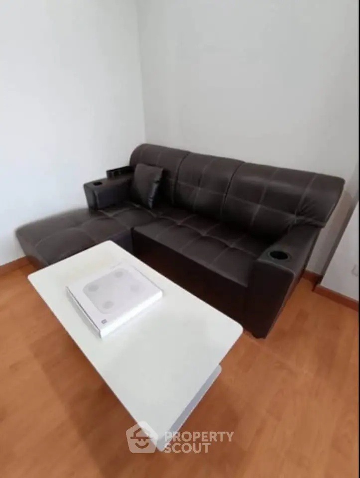 Modern living room with sleek black sofa and stylish white coffee table on wooden flooring.
