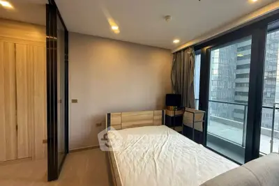 Modern bedroom with large windows and city view, featuring a minimalist design and ample natural light.