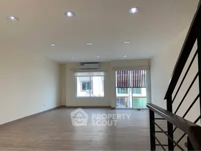 Spacious modern living room with wooden flooring and large windows for natural light.