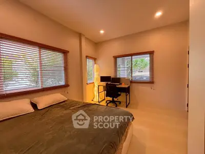 Cozy bedroom with study area and large windows offering natural light