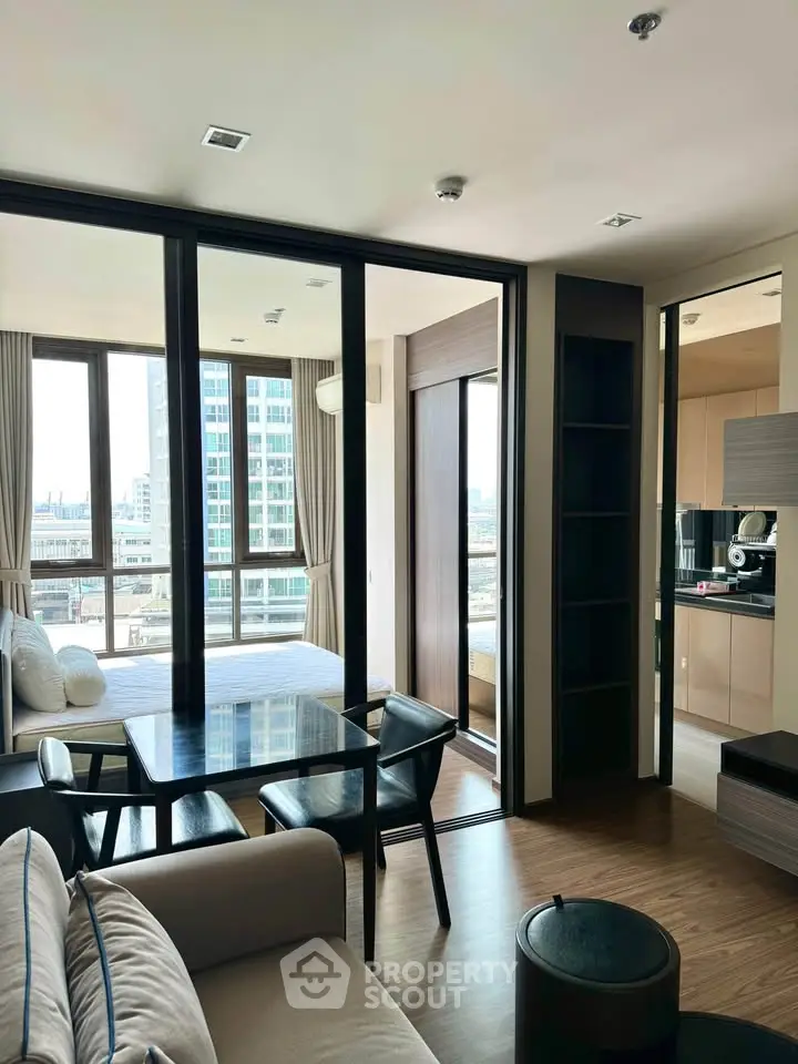 Modern living room with large windows and city view, featuring stylish furniture and open layout.