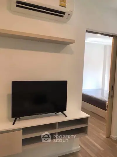 Modern apartment interior with TV and air conditioning, showcasing sleek design and cozy bedroom view.